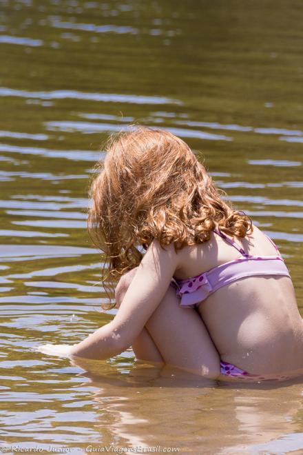 Imagem de uma menina aguachada na piscina natural.